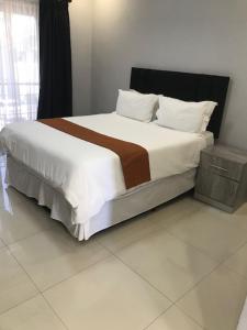 a bedroom with a large bed with white sheets and pillows at Innisfree Apartments in Gaborone +23 photos