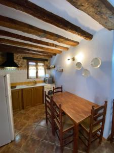 a kitchen and dining room with a wooden table at Mas de Nofre in Peñarroya de Tastavins