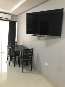 a dining room with a table and a television on a wall at Innisfree Apartments in Gaborone