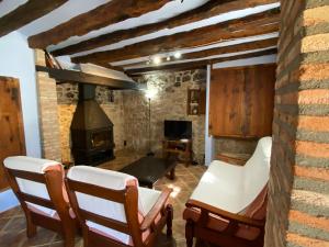 uma sala de estar com cadeiras e um fogão a lenha em Mas de Nofre em Peñarroya de Tastavíns