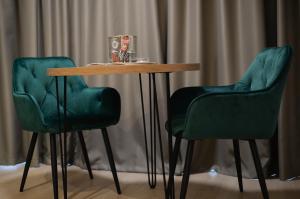 two green chairs around a wooden table with a green table at Nia Lux Apartman in Belgrade