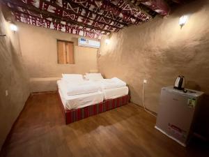 a small room with two beds and a phone in it at AL Hamra Heritage Inn in Al Ḩamrāʼ