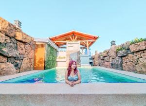 una mujer sentada en el agua en una piscina en Siargao Vibes Private Resort en Bago