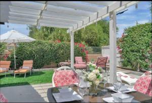 une terrasse avec une table et des chaises sous une pergola blanche. dans l'établissement The Coachella Gem weekly discounts, à Coachella