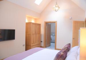 a bedroom with a bed and a flat screen tv at Lily Rose Cottage in Broadway