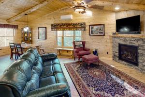 sala de estar con sofá de cuero y chimenea en Blackbear Log Cabin en Morrisville