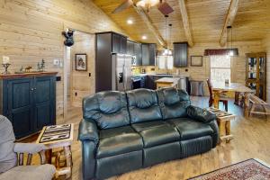 a living room with a leather couch and a kitchen at Blackbear Log Cabin in Morrisville