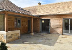 a wooden house with a patio in front of it at Lily Rose Cottage in Broadway