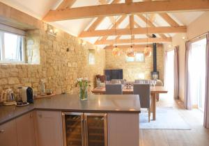 a kitchen with a table and a stone wall at Lily Rose Cottage in Broadway