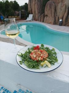 a plate of salad and a glass of wine next to a pool at B&B Rena Majore con piscina privata! in Rena Majore
