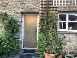 uma casa de pedra com uma porta de madeira e uma janela em Stable Cottage em Blaenporth