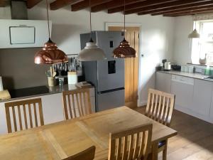 uma cozinha com uma mesa de madeira e uma cozinha com um frigorífico em Stable Cottage em Blaenporth