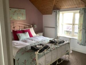 a bedroom with a bed with red pillows and a window at Stable Cottage in Blaenporth