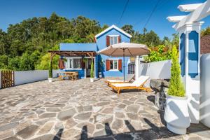 una casa y un patio con sombrilla y sillas en Blue House - By Wehost, en Ponta do Sol
