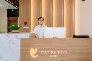 a man standing behind a desk with a laptop at CAT BA ECO HOTEL in Cat Ba