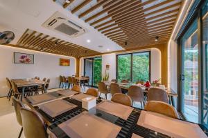 uma sala de jantar com mesas, cadeiras e janelas em CAT BA ECO HOTEL em Ilha de Cát Bà