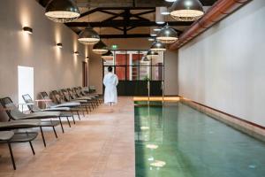 a woman in a white dress is standing next to a swimming pool at Valverde Santar Hotel & SPA - Relais & Châteaux in Santar