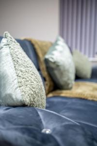 a blue couch with two pillows on top of it at 2-Bedroom Cozy Hideaway Close to Hollingworth Lake in Milnrow in Rochdale