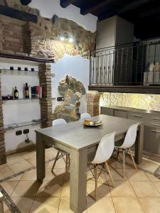 kuchnia z drewnianym stołem i białymi krzesłami w obiekcie Casa Vacanza al Centro di Iglesias tra Mare e Miniere w mieście Iglesias