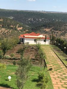 een wit gebouw met een rood dak op een heuvel bij Maison Ain Lakssab in Ben Slimane