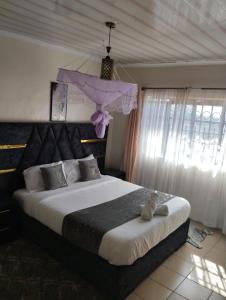 a bedroom with a large bed with a purple head board at Exquisite 2BR Ensuite Apartment close to Rupa Mall, Mediheal Hospital, and St Lukes Hospital in Eldoret