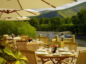 a patio with tables and chairs with a view of a river at Terelj Hotel & Spa in Ulaanbaatar