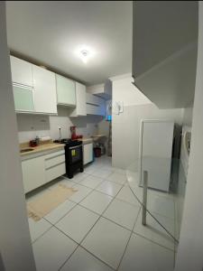 uma cozinha com armários brancos e piso em azulejo branco em Apart. 2/4 - 500 mts da praia.Ilhéus em Ilhéus