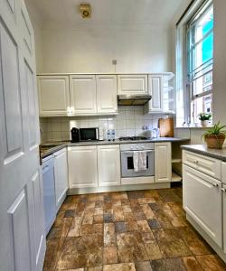 a kitchen with white cabinets and a tile floor at Lovely One Bedroom Appartment in Marylebone Central London - 4 people in London