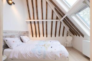 1 dormitorio con cama blanca y techo de madera en Iselmarpleats 3 kamer appartement, en Gaast