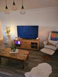 a living room with a tv and a chair and a coffee table at Serviced Apartment - Aberdeen in Dyce