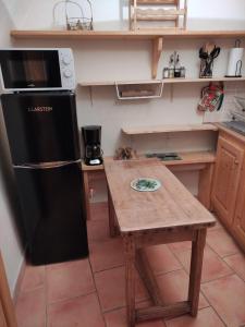 a kitchen with a black refrigerator and a wooden table at Chambre atypique : La Grotte in Bez-et-Esparon