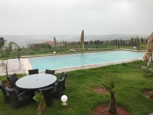 een zwembad met een tafel en stoelen in een tuin bij Maison Ain Lakssab in Ben Slimane