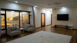 - un salon avec deux chaises et une télévision à écran plat dans l'établissement استراحة الكثبان, à Ḩawīyah