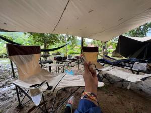 una persona sdraiata su una sedia sotto una tenda di CAMPSITE CMM YAN KEDAH a Yan