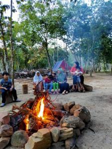 un grupo de personas sentadas alrededor de un campamento de fuego en CAMPSITE CMM YAN KEDAH en Yan