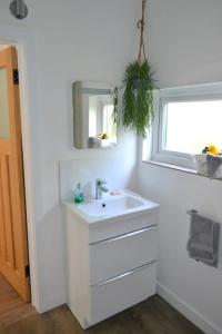 a white bathroom with a sink and a window at The Garden Lodge in Shaldon