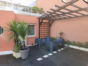 a patio with a table and chairs under a pergola at Le cours Donville, appart neuf à 100m de la mer in Donville-les-Bains