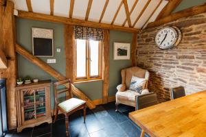 a living room with a clock on the wall at Meadow End Barn in Dorstone