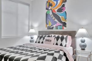 ein weißes Schlafzimmer mit einem schwarz-weißen Bett und einem Gemälde in der Unterkunft 10 Cozy apartment heart of Santa Monica in Los Angeles