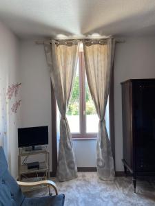 a living room with a window with curtains at Chambre Nuit d'Asie in Montournais +8 photos