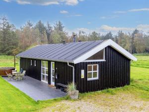 Three-Bedroom Holiday home in Øster Assels 3 في Sillerslev: كابينة سوداء مع سطح في حقل