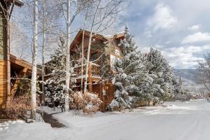 a log cabin in the snow next to some trees at Christiana Lodge 102A Studio in Aspen with Hot Tub access in Aspen