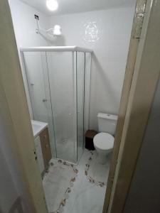 a bathroom with a toilet and a glass shower at Pequeno, más aconchegante in Itapema