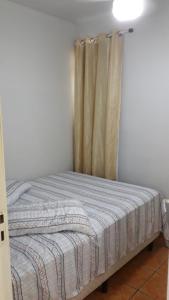 a bed in a room with a curtain at Pequeno, más aconchegante in Itapema