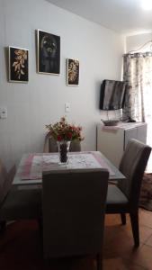 a dining room table with a vase of flowers on it at Pequeno, más aconchegante in Itapema