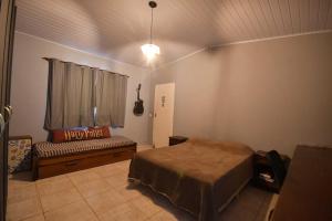 ein Schlafzimmer mit einem Bett, einem Sofa und einem Fenster in der Unterkunft Chácara Recanto do Sossego in Igaratá