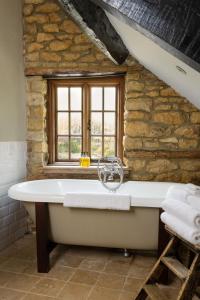 a bath tub in a stone bathroom with a window at The Ebrington Arms in Chipping Campden