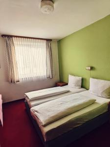 2 camas en una habitación con paredes verdes y ventana en City Hotel Bauer mit Aufzug with elevator, en Núremberg