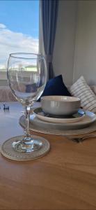 un bicchiere di vino seduto sopra un tavolo di Herons Mead Touring Park and Fishing Lakes - Plot 18 a Orby
