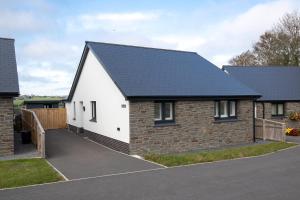 a house with a black roof and a driveway at The Paddock - Lovely Cottage with Hot Tub in Penally